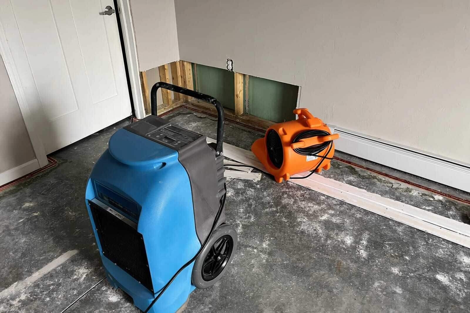 Air movers and a dehumidifier drying a water-damaged room in a Houston home