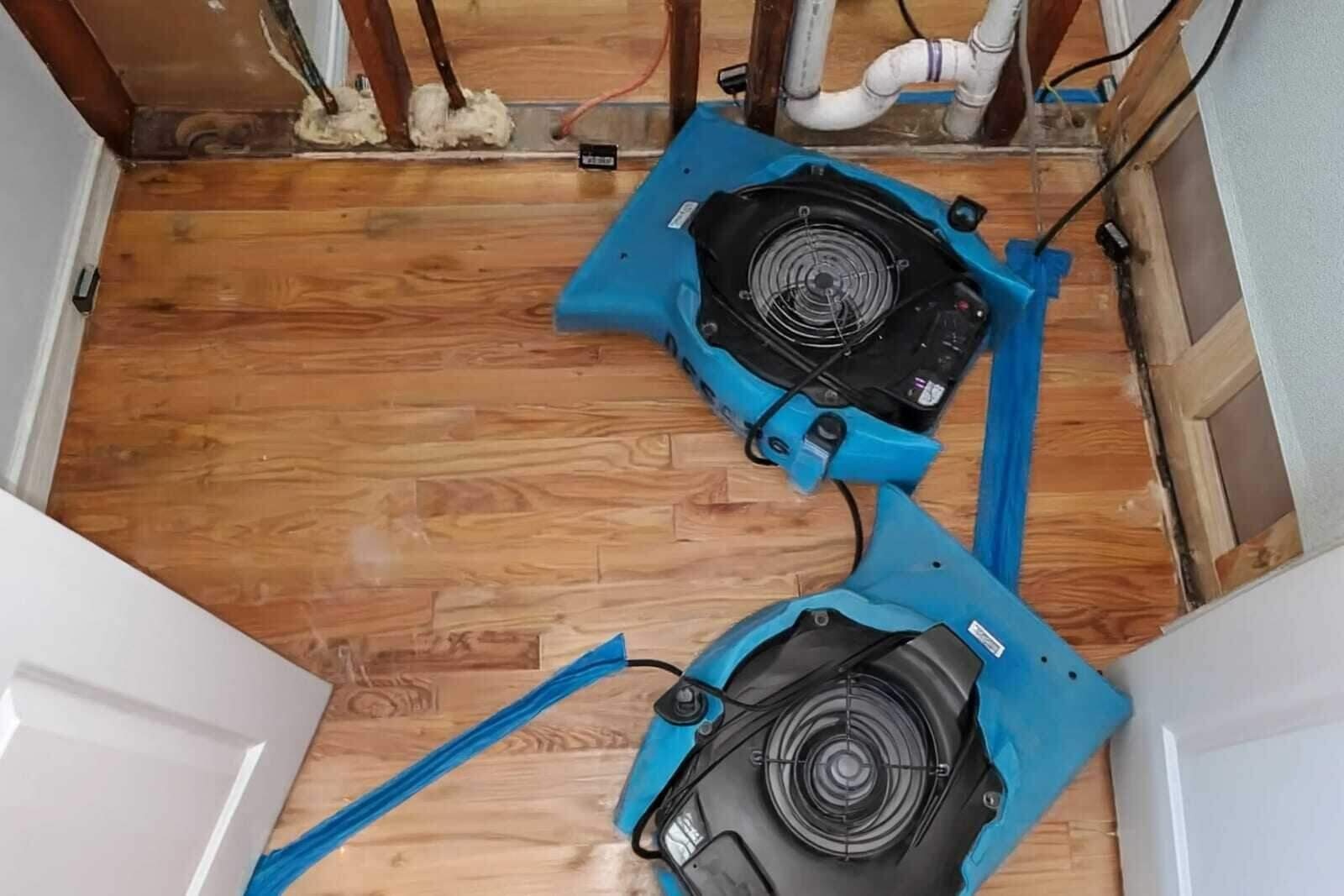 Air movers and a dehumidifier drying a Houston home after a burst pipe
